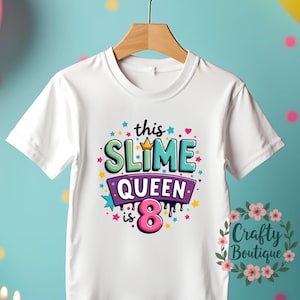 以下が含まれることがあります： 「This Slime Queen is 8」とカラフルなグラフィックがプリントされた白いTシャツです。