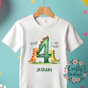 May include: White t-shirt with a green number four, two orange and yellow dinosaurs, and the text "Roar I am Four Joshua".