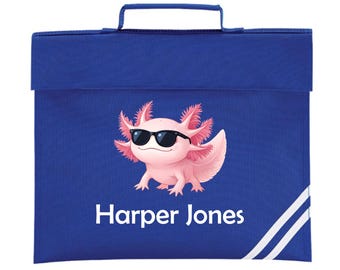 May include: A royal blue school bag featuring a pink axolotl wearing sunglasses. The bag has a handle and a flap closure. The name "Harper Jones" is printed in white. White stripes accent the lower right corner.