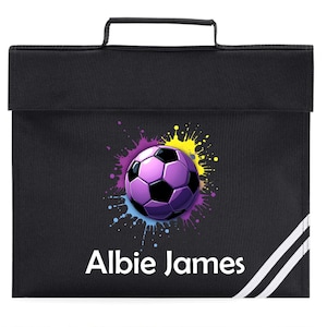 May include: Black school satchel with a handle, featuring a purple and black football graphic on a colourful splash background. The name "Albie James" is printed in white. White stripes run down the right side of the satchel.
