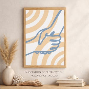 Può includere: Una stampa artistica da parete rettangolare in una cornice di legno con un disegno a linee blu di due mani che si tengono l'una con l'altra su uno sfondo di strisce curve alternate bianche e arancioni chiare. Il testo sotto recita SUGGESTION DE PRÉSENTATION.