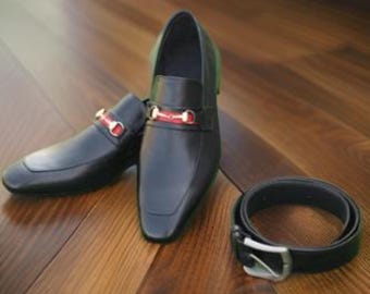 Peut inclure: Une paire de chaussures habillées en cuir noir avec un détail de boucle rouge et or. Une ceinture en cuir noir avec une boucle argentée est également représentée.