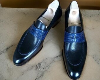 May include: A pair of dark blue leather loafers with a blue crocodile-embossed leather strap across the vamp.
