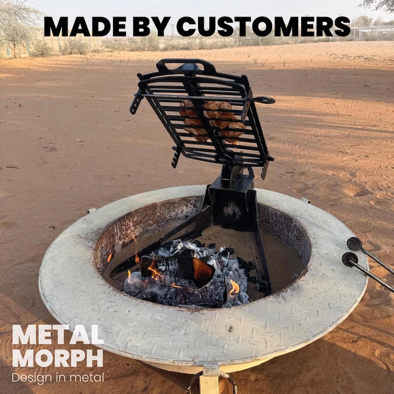 Puede incluir: Una parrilla de metal negro ajustable montada sobre una base circular de color claro para fogata con textura de placa de diamante. La parrilla sostiene alimentos sobre un fuego de le&ntilde;a. Texto superior MADE BY CUSTOMERS e inferior METAL MORPH Design in metal.