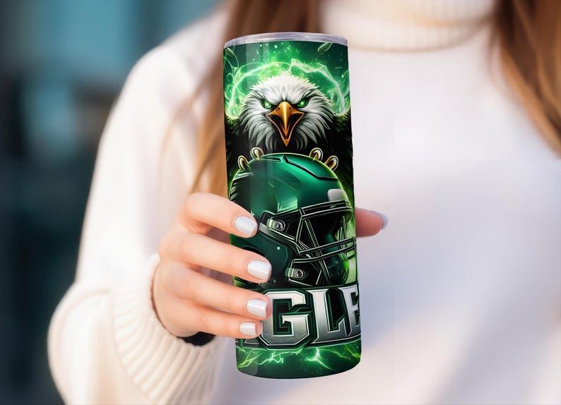 May include: Green and black stainless steel tumbler featuring a graphic of a bald eagle holding a football helmet. The text "EAGLES" is printed on the tumbler.