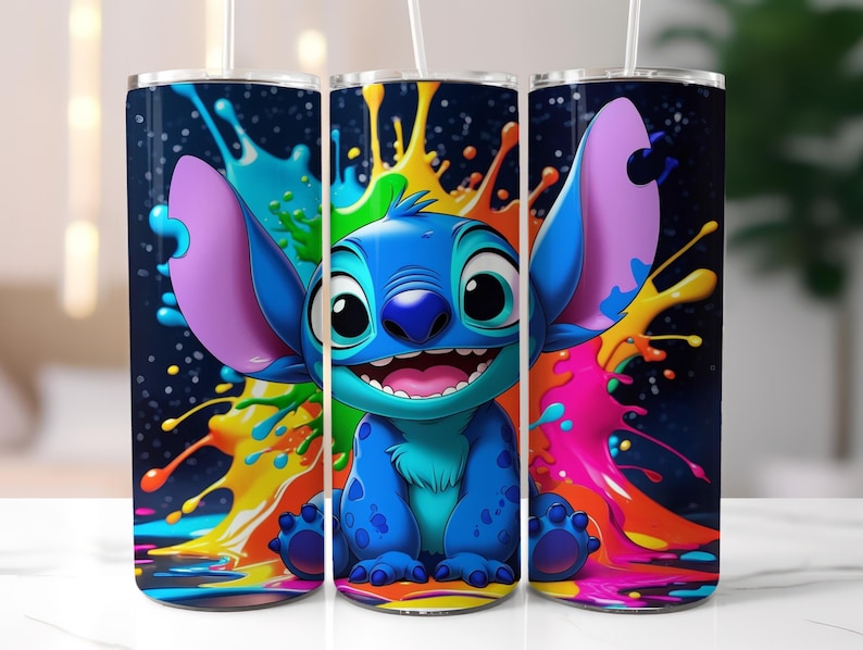 Puede incluir: Tres vasos de acero inoxidable con un dise&ntilde;o colorido que presenta al personaje de dibujos animados Stitch. El dise&ntilde;o muestra a Stitch sobre un fondo de salpicaduras de pintura de varios colores. El personaje es azul con orejas grandes y una expresi&oacute;n alegre.