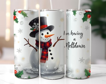 May include: A white tumbler featuring a snowman wearing a black top hat, a red and black plaid scarf, and a carrot nose. The tumbler has the text "I'm having a Meltdown" and is decorated with snowflakes and holly.