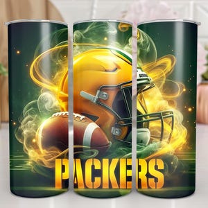 Pode incluir: Tr&ecirc;s copos verdes e dourados com um capacete de futebol e bolas de futebol em um design esfuma&ccedil;ado. Os copos t&ecirc;m a palavra "PACKERS" impressa.