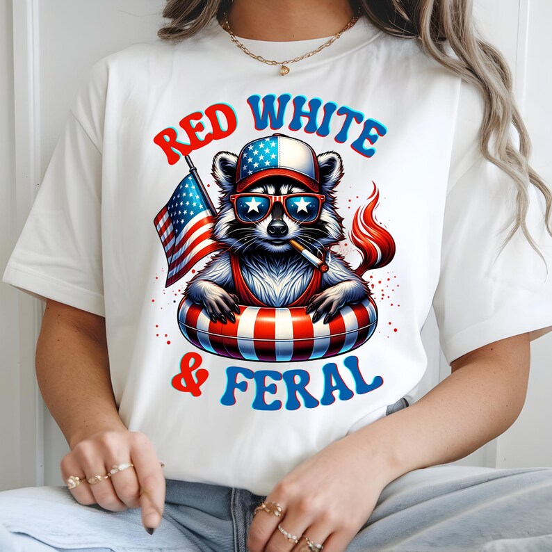 May include: White t-shirt with a raccoon design wearing sunglasses, a hat, and a life preserver, holding an American flag and a cigarette. The text on the shirt reads "Red White & Feral" in red and blue.