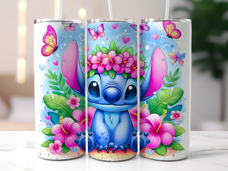 May include: Three white insulated tumblers with a colorful cartoon design featuring a blue alien character wearing a flower crown, surrounded by pink flowers, butterflies, and green leaves. Each tumbler has a white straw.