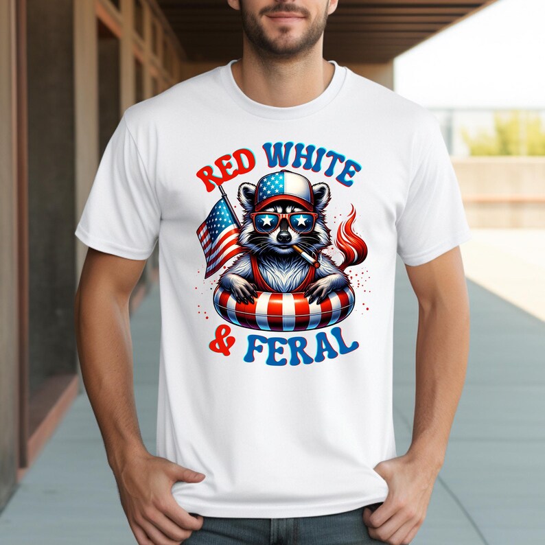 May include: White t-shirt with a cartoon raccoon wearing sunglasses, a hat, and an inner tube, holding an American flag and a lit cigarette. The text on the shirt reads "Red White & Feral" in red and blue.
