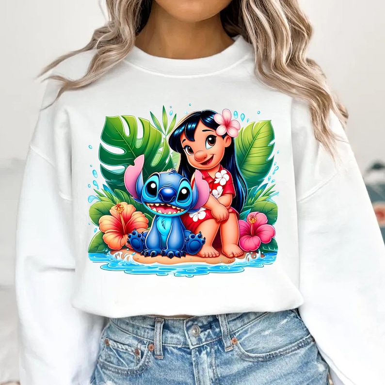 Pu&ograve; includere: Felpa bianca con una grafica colorata di Lilo e Stitch. Il design mostra Lilo in un vestito rosso con un fiore tra i capelli e Stitch accanto a lei. Fiori e foglie tropicali li circondano.