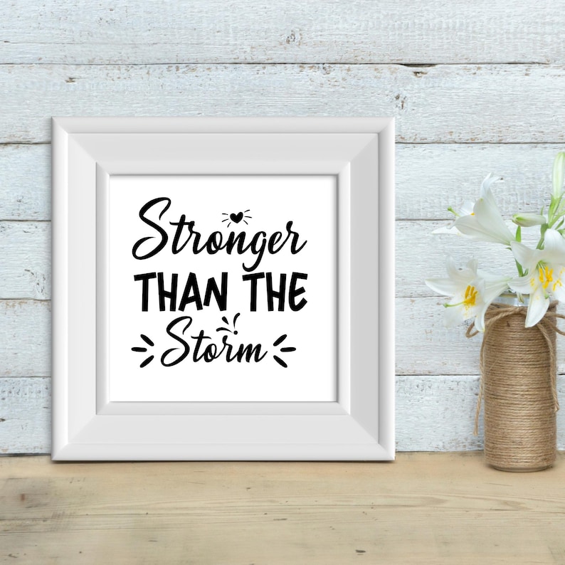 May include: White framed print with black text that reads "Stronger Than The Storm" with a small heart symbol above the word "Stronger".