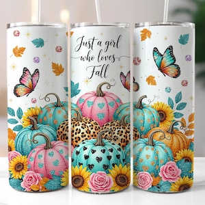 May include: A white tumbler featuring a fall-themed design with pumpkins, sunflowers, butterflies, and the text "Just a girl who loves Fall." The pumpkins are teal, pink, and orange with heart and leopard print patterns.