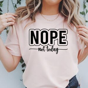 Op de afbeelding: Een roze T-shirt met de tekst "NOPE not today" in zwarte letters.