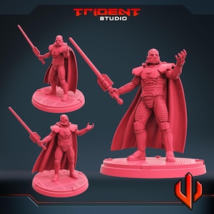 May include: A red figurine of a character with a helmet, cape, and lightsaber. The figure is standing on a circular base. The Trident Studio logo is at the top.