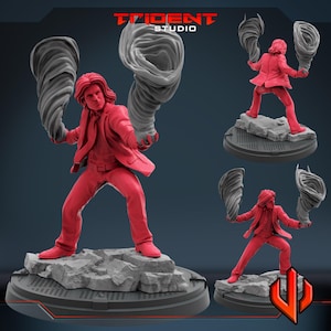May include: A red figurine of a person in a suit, holding two gray tornado-like shapes. The figure stands on a rocky base. The Trident Studio logo is visible in the top right corner.