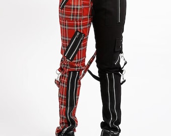 May include: Split-design pants featuring a red plaid pattern on one leg and solid black on the other. The pants have multiple zippers, straps, and silver hardware. The model is wearing black platform boots. The pants are a unique fashion statement.