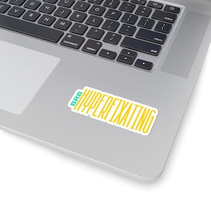 May include: A white laptop with a yellow and teal sticker that says "BRB HYPERFIXATING".