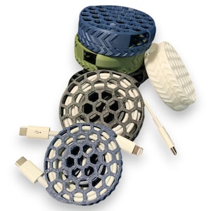 May include: Four cable organizers in different colors, blue, green, gray, and white. Each organizer is a round, honeycomb-shaped design with a cable running through it.