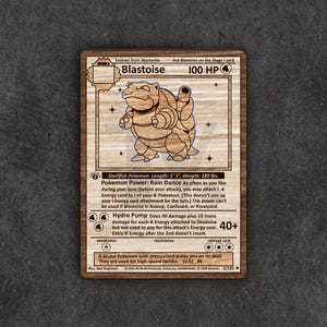 Może przedstawiać: Karta Pokémon Blastoise z Gry Karcianej Kolekcjonerskiej Pokémon. Karta jest brązowa z niebieską obwódką i przedstawia ilustrację Blastoise'a, dużego, niebieskiego, podobnego do żółwia Pokemona z armatkami wodnymi na grzbiecie. Karta ma moc zwaną Tańcem Deszczu i atak zwany Hydro Pompą. Karta pochodzi z 2. edycji Gry Karcianej Kolekcjonerskiej Pokémon.