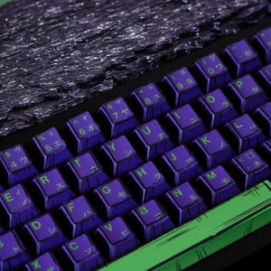 May include: A purple and green keyboard with Japanese characters on the keys. The keyboard has a textured, black surface on the top.