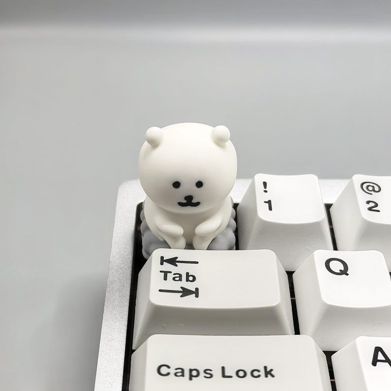 May include: A white keyboard with a small white bear figurine sitting on the "Tab" key. The bear is sitting on a small gray cloud.