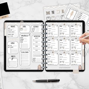 May include: A black and white planner with sections for weight, sleep, fitness, and nutrition. The planner includes a weekly weight loss tracker, habit tracker, and goal setting pages. The image also includes a pen, stickers, and a before and after photo frame.