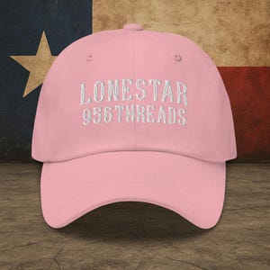 May include: A pink baseball cap with white embroidered text that reads "LONESTAR 956THREADS".