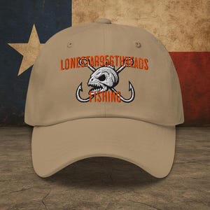 May include: A tan baseball cap with an embroidered design of a skull with crossed fishing hooks. The text "Lonestar956threads Fishing" is embroidered in orange on the front of the cap.