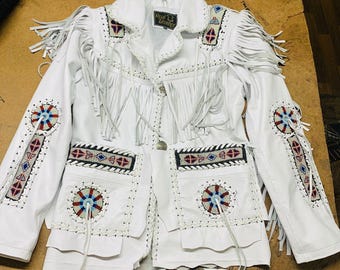 May include: White leather jacket with fringe and beaded details. The jacket has a zip closure and two pockets. The label on the jacket reads "Real Leather".
