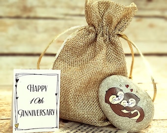 May include: A small hessian bag containing a painted stone. The stone depicts two otters embracing and the words "Happy 10th Anniversary".