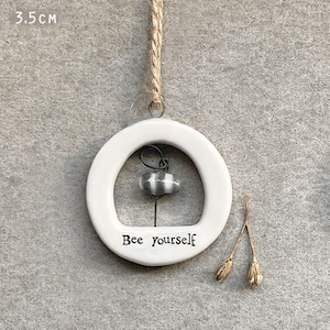May include: A white ceramic wind chime with the text "Bee yourself". The chime has a silver bell inside a circular frame, suspended by a natural rope. The diameter is 3.5 cm (approx. 1.4 inches).