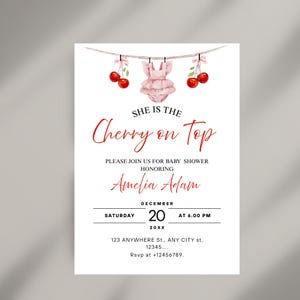 Puede incluir: Invitación a un baby shower con fondo blanco y texto rojo. La invitación presenta una ilustración de acuarela de cerezas y un atuendo de bebé rosa. El texto dice "She is the Cherry on Top" y los detalles del baby shower de Amelia Adam.