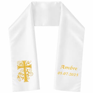 May include: White satin stole with gold embroidered cross and floral design. The stole has the name "Ambre" and the date "05.07.2025" embroidered in gold. The stole is likely for a religious ceremony.