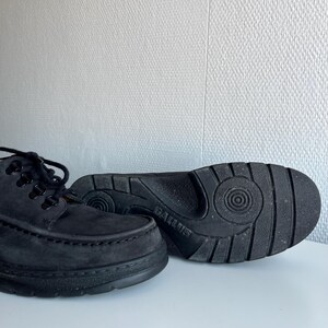 May include: A pair of black suede lace-up shoes with thick soles. The shoes have a classic design with visible stitching and a textured sole for grip. The brand name "GALLUS" is visible on the sole of one shoe.