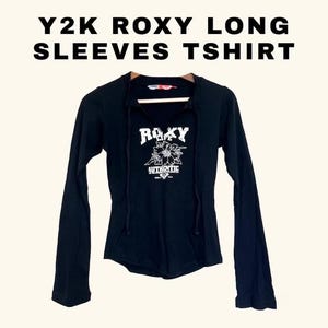 May include: Black long-sleeved t-shirt with a white graphic of a flower and the text "Roxy Life Authentic".