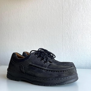 May include: A pair of black suede shoes with thick soles. The shoes have a lace-up design and a rounded toe. The soles are made of a durable material, and the shoes appear to be unworn.