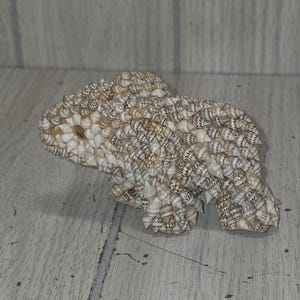 May include: A white ceramic mug with a black handle and the text "But First, Coffee" in a black, handwritten-style font. The mug is on a white surface.