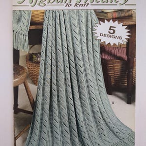 May include: A book cover titled "Afghan Medley to Knit" featuring a light green knitted afghan with a fringed edge. The cover also displays a smaller knitted piece with fringe and a starburst graphic with "5 DESIGNS".