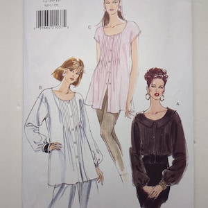 Könnte beinhalten: Vogue Patterns 9201 Schnittmusterumschlag für die Größen 12-14-16. Die Vorderseite zeigt Illustrationen von drei Blusenvarianten: ein weißes Oberteil mit langen Ärmeln, ein hellrosa Oberteil mit kurzen Ärmeln und ein dunkelbraunes Oberteil mit langen Ärmeln.