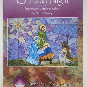 May include: A book cover titled O Holy Night Impressionist Stained Glass by Brenda Henning. The cover features a stained glass style illustration of a nativity scene with a star, figures, and a lamb. The bottom includes the Bear Paw Productions logo.