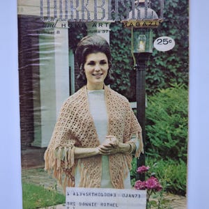 May include: A vintage copy of "The Workbasket and Home Arts Magazine" from May 1972, with a woman wearing a crocheted shawl. The magazine cover has the price of 25 cents. The woman is standing in front of a green background.