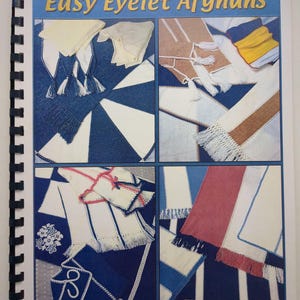 May include: A spiral-bound instructional book titled Easy Eyelet Afghans by Eileen Montgomery. The cover features four distinct photographic panels displaying various crocheted afghans in blue, white, tan, yellow, and pink with fringe details.