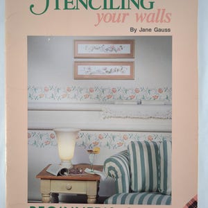 Könnte beinhalten: Eine weiße Keramik-Tasse mit schwarzem Henkel und dem Text "But First, Coffee" in fetter, schwarzer Schrift. Die Tasse steht vor einem verschwommenen Hintergrund, der ihr klares Design hervorhebt.