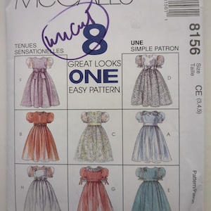 May include: A McCall's 8156 sewing pattern envelope for children's dresses in size CE (3, 4, 5). The white paper envelope features illustrations of eight different dress variations with puff sleeves and full skirts, labelled A through H.