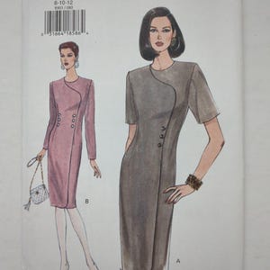 Könnte beinhalten: Ein Very Easy Very Vogue Schnittmusterumschlag 8903 für die Größen 8-10-12. Die Abbildung zeigt zwei Kleider-Varianten: ein malvenfarbenes Kleid mit langen Ärmeln und ein graues Kleid mit kurzen Ärmeln, beide mit geschwungener Frontnaht.