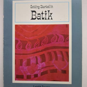 May include: A softcover book titled Getting Started in Batik by Astrith Deyrup. The cover features a blue border and a central rectangular image displaying a red and pink fabric pattern with wavy lines, leaf shapes, and dark rectangular blocks.
