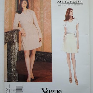 May include: An Anne Klein Vogue American Designer sewing pattern envelope, number 1626, featuring a photograph of a beige double-breasted coat dress and a fashion illustration of a white short-sleeved top paired with a light-coloured skirt.