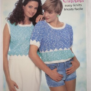 May include: A vintage magazine cover showing two women wearing knitted tops. The tops are in shades of blue and white, with a scalloped edge design. The text "Patons Carolina easy knits tricots facile" is displayed.